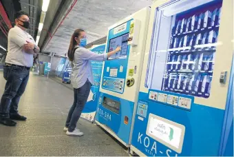  ?? SOMCHAI POOMLARD ?? LEFT
A woman purchases 25-baht fabric masks at the Makkasan Airport Rail Link station.