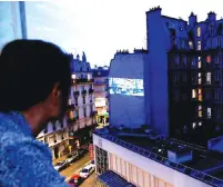  ?? (Gonzalo Fuentes/Reuters) ?? CHRISTINE DAVENIER watches the film ‘Man Without a Star’ as it is projected on the wall of an apartment building in Paris, last week.