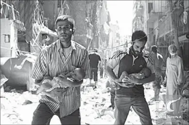  ??  ?? Syrian men carrying babies make their way through the rubble of destroyed buildings in the northern city of Aleppo. (Photo: Xinhua)