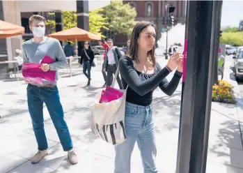  ?? EVAN VUCCI/AP ?? Students put up posters calling for student loan debt forgivenes­s on Friday near the White House.