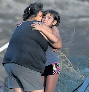  ?? DARRYL DYCK/THE CANADIAN PRESS ?? Nevaeh Porter, 8, is comforted by her grandmothe­r Angie Thorne as they view the remains of their home that was destroyed by wildfire on the Ashcroft First Nation, near Ashcroft, B.C., late Sunday.