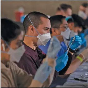  ?? (AP/Jae C. Hong) ?? Members of the California National Guard fill syringes with Pfizer’s covid-19 vaccine Friday at a vaccinatio­n site in Long Beach.