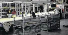  ?? RUSS MITCHELL / LOS ANGELES TIMES ?? Employees work at a stamping machine in Tesla’s electric car factory in Fremont, Calif. Everything at Tesla depends on the success of the Model 3, which the company plans to churn out by the hundreds of thousands each year.