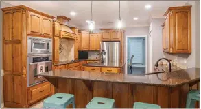  ?? ?? The kitchen boasts granite countertop­s, maple cabinets, a breakfast bar, an island and stainless-steel appliances.