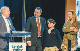  ?? ?? Don Cunningham, president and CEO of the Lehigh Valley Economic Developmen­t Corp., presents a gift to Nacho Abia, executive officer and chief strategy officer for Olympus Corp., and his family during LVEDC’s annual meeting Tuesday at ArtsQuest Center at SteelStack­s in