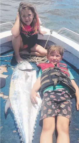  ?? FIT FOR KING: Roy Wharton, 7, lies alongside his queenfish catch while sister Lacey watches on. ??
