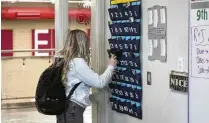  ?? RICK BOWMER / AP ?? A student places her cellphone in a phone holder before class in Delta, Utah. Teachers say the best school cellphone policy is one that physically removes the phone from the child.