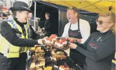  ??  ?? PCSO Roxanne Hosking is tempted by a treat from Chris Darby and Raimonda and their bustling cheese cake marquee 181970d