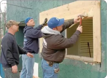  ??  ?? Master carpenter Mike Cox, foreground, gets an assist in fixing up the concession stand window.