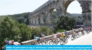  ??  ?? NIMES: File photo taken on July 23, 2019 France’s Julian Alaphilipp­e (front centre), wearing the overall leader’s yellow jersey and cyclists cross the Pont du Gard during the sixteenth stage of the 106th edition of the Tour de France cycling race between Nimes and Nimes, in Nimes. —AFP