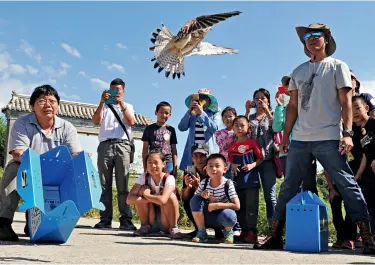  ??  ?? Zhou Lei (à g.) et des élèves libèrent des oiseaux aux Collines parfumées de Beijing le 10 septembre 2016.