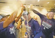  ?? JAE C. HONG/ASSOCIATED PRESS ?? The Dodgers’ Max Muncy, right, sprays Cody Bellinger, center, with Champagne and beer in the clubhouse after the team’s win against the Rockies in a tiebreaker Monday in Los Angeles.