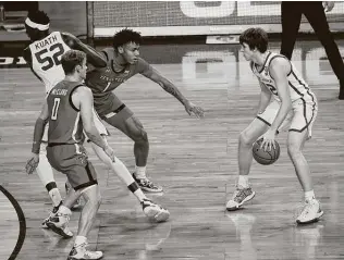  ?? Garett Fisbeck / Associated Press ?? Oklahoma’s Austin Reaves, right, surveys the court as Kur Kuath (52) slips between Texas Tech’s Mac McClung (0) and Terrence Shannon Jr. during the first half Tuesday night.