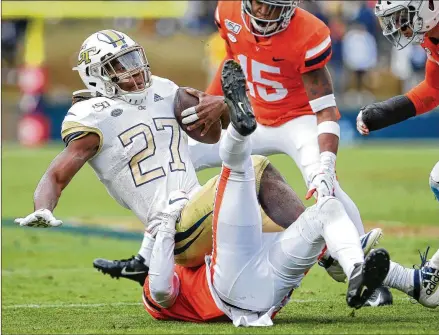  ?? RYAN M. KELLY / GETTY IMAGES ?? Tech running back Jordan Mason is tackled by Virginia’s Nick Grant in the second half Saturday, as the Yellow Jackets fall to the Cavaliers for the 12th time in 14 meetings at Charlottes­ville, Virginia.