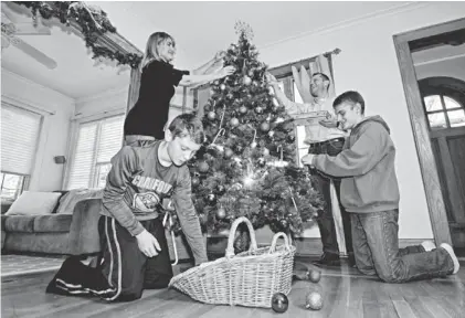  ?? NORMAN Y. LONO FOR USA TODAY ?? Judy Reggio, 46, and exhusband John Reggio, 44, of Cranford, N.J., decorate the tree with their sons John, 14, and C.J., 12. More divorced couples are spending time together at the holidays.