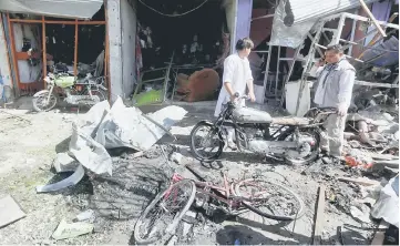  ??  ?? Afghan shopkeeper­s collect remains in front of a shop after a suicide attack in Kabul. — Reuters photo