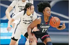  ?? GARY LANDERS/AP PHOTO ?? UConn’s Christyn Williams, right, takes control of a loose ball in front of Xavier’s Shaulana Wagner during Saturday’s game in Cincinnati. Williams scored 22 points as the No. 1 Huskies clinched at least a share of the Big East title with an 83-32 win over the Musketeers.
