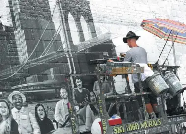  ?? DON EMMERT / AGENCE FRANCE-PRESSE ?? Artist Liam Williams paints an advertisem­ent on the side of the Colossal Media office building in New York.