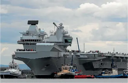  ?? PHOTO: REUTERS ?? The aircraft carrier HMS Queen Elizabeth - the largest warship Britain has ever had - is eased out of its berth at a shipyard in Rosyth by tugs before setting off on its maiden voyage, starting six weeks of sea trials.