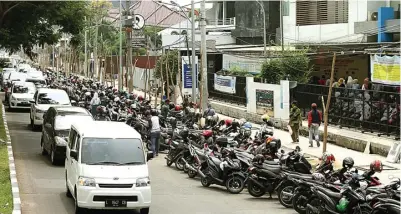  ?? ROBERTUS RISKY/JAWA POS ?? JALUR SEMPIT: Parkir sepeda motor di timur kantor BPJS Kesehatan Cabang Surabaya menghabisk­an satu lajur di Jalan Dharmahusa­da Indah.