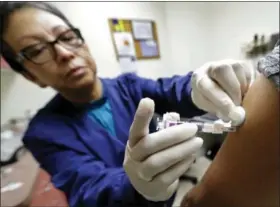  ?? TED S. WARREN — THE ASSOCIATED PRESS ?? Ana Martinez, a medical assistant at the Sea Mar Community Health Center, gives a patient a flu shot, Thursday in Seattle. According to an update by the Centers for Disease Control and Prevention released Friday flu is now widespread in every state...