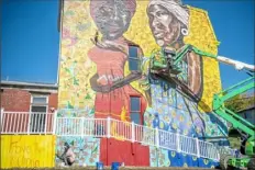  ?? Alexandra Wimley/Post-Gazette ?? Ray Butler, of Morningsid­e, who goes by his artist name AmunRay, and artist Kyle Holbrook, lower left, work on a mural that is part of the Pittsburgh Solidarity for Change project Saturday in the Hill District.