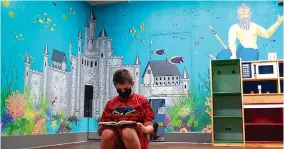  ?? Staff photos by Neil Abeles ?? ■ RIGHT: Isaac Harwell, 11, is reading just outside a magical castle in the children’s basement of the Atlanta Public Library.