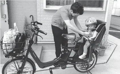 ??  ?? Preparando para llevar a la guardería a Emilie, su hija de un año y medio en la bicicleta con motor en la que recorren Tokio.