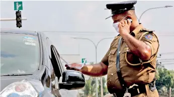  ??  ?? Colombo: Curfew pass being checked. Pic by Sameera Weeraseker­a