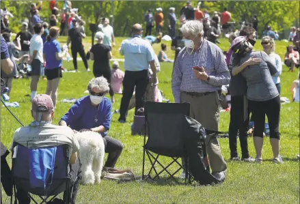  ?? Olivier Douliery / AFP via Getty Images ?? People wearing face masks gather in a park to watch the U.S. Navy Blue Angels and U.S. Air Force Thunderbir­ds fly over the Washington area on Saturday, in a tribute to essential workers during the coronaviru­s pandemic.