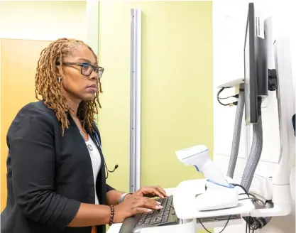  ?? TYLER PASCIAK LARIVIERE/SUN-TIMES ?? Karie E. Stewart, Certified Nurse Midwife at UI Health, works on a computer in an exam room at UI Health Mile Square Primary and Immediate Care Center in Auburn Gresham.