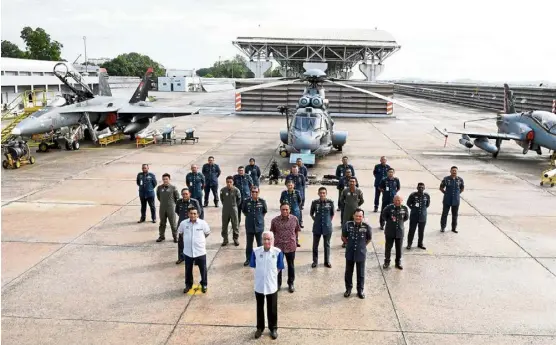  ??  ?? Standing at attention: Ismail Sabri (centre) and Reezal (in red) with MaF officers posing in front of fighter jets during their visit to the Butterwort­h air base. — Bernama