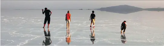  ??  ?? Travellers admire their reflection­s in the massive salt flats of the Afar Region. Salt is the main resource of the Danakil, and about 700 registered miners work in the Ethiopian lowland.