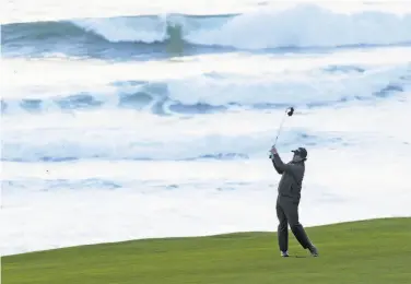  ?? Harry How / Getty Images ?? Phil Mickelson plays a shot on No. 10 at Pebble Beach. After his tee time was pushed back more than three hours, he took a three-shot lead through 16 holes. He and Paul Casey will complete their rounds Monday.