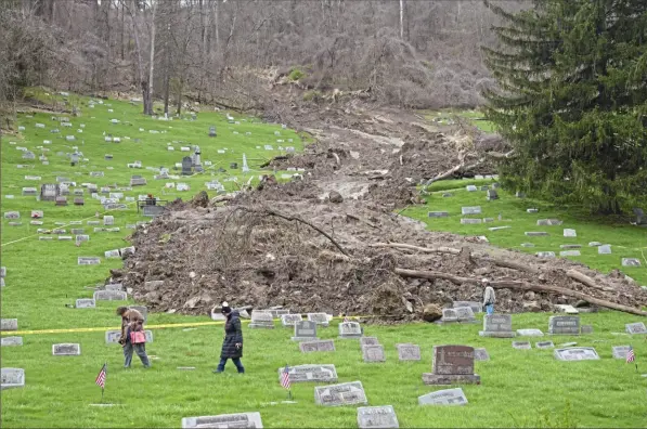  ?? Sebastian Foltz/Post-Gazette photos ?? Family members check on the graves of relatives in the Wheeling Mt. Zion Cemetery on Saturday following a landslide last week caused by heavy rainfall in and around Wheeling, W.Va. Volunteers who take care of the cemetery say they believe vaults below the markers were not affected.
