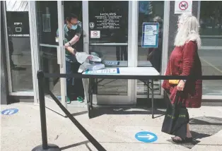  ?? BRANDON HARDER ?? Catherine Robertson waits outside RPL’S Central branch to pick up books and DVDS requested from the curbside pickup program. All library branches are expected to reopen by July 13.