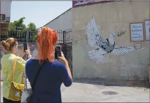  ?? (AP/Nasser Nasser) ?? Tourists take photos of a mural by Banksy on Aug. 4 in the West Bank city of Bethlehem.