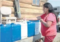  ??  ?? Many homes lack running water, such as Betty Lulua’s log cabin where she and her husband haul creek water in 20-litre jugs.