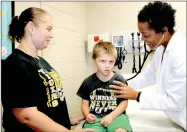  ?? LYNN KUTTER ENTERPRISE-LEADER ?? Marie Chantal Crosse, family nurse practition­er with Prairie Grove Health & Wellness Center, gives Charles Phipps, 5, of Prairie Grove, a kindergart­en physical while his mom, Sylvia Phipps gives moral support.