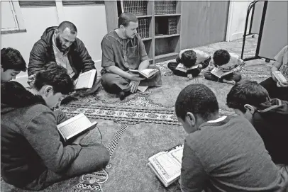  ?? [FRED SQUILLANTE/DISPATCH] ?? Mohamed Djebbari, center rear, leads a Quran-memorizati­on class at Masjid Omar Ibn El-khattab. Djebbari has acted for the past five years as the North Side mosque’s unofficial imam. On his right is board member Mohammad Dada.