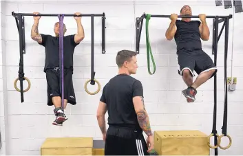  ?? GREG SORBER/JOURNAL ?? Jason Garcia, left, and Leroy Sanchez do pull-ups with trainer Barry Ore during an Addicts2At­hletes session at Duke City Strength Gym for people recovering from addiction.