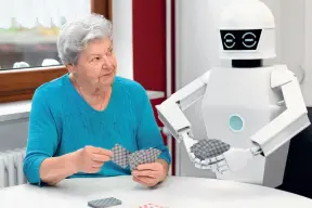  ??  ?? Un robot joue aux cartes avec une retraitée.
