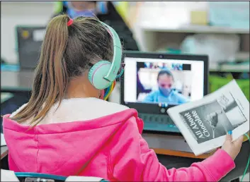  ?? Eric Gay The Associated Press ?? Students at Driggers Elementary School attend a class in-person as they interact with classmates virtually last year in San Antonio.