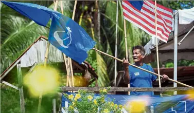  ??  ?? Final touches: Barisan supporter Ibrahim Mat Isa, 62, putting up the party flag in his front yard ahead of the by-election. — Bernama