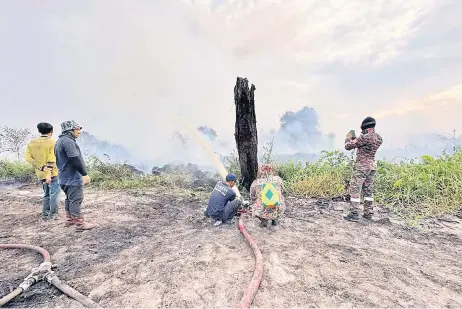  ?? — Bomba photo ?? Bomba personnel and volunteers battle the fire in Kuala Baram on Sunday.