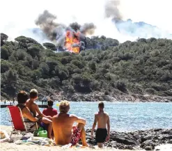  ?? —AFP ?? People enjoy the beach as they look at a forest fire in La Croix-Valmer, near SaintTrope­z.