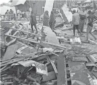  ?? FARAH ABDI WARSAMEH/AP ?? People look at destroyed shops in Mogadishu’s Lido beach, Somalia, on April 23 after a bomb blast by Somalia’s Islamic extremist rebels hit a popular seaside restaurant, killing at least six people.