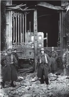  ??  ?? ■ Naval troops pose in front of the gates of the Berlin Palace after the artillery bombardmen­t. Note that the man on the left has removed the national cockade from his cap.