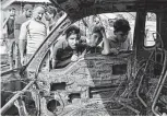  ?? Associated Press ?? Boys peer inside a damaged vehicle at the scene of an explosion at a crowded outdoor used furniture market in the Sadr City area of Baghdad.