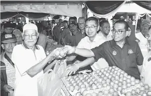  ?? — Gambar Bernama ?? SUMBANGAN: Mohamed Khaled (dua kanan) dan Tan Cher Puk (tiga kanan) mengagihka­n telur kepada penduduk Flat Tasek 64 selepas melancarka­n Pasar Komuniti Jauhar di Seri Alam, Pasir Gudang semalam.